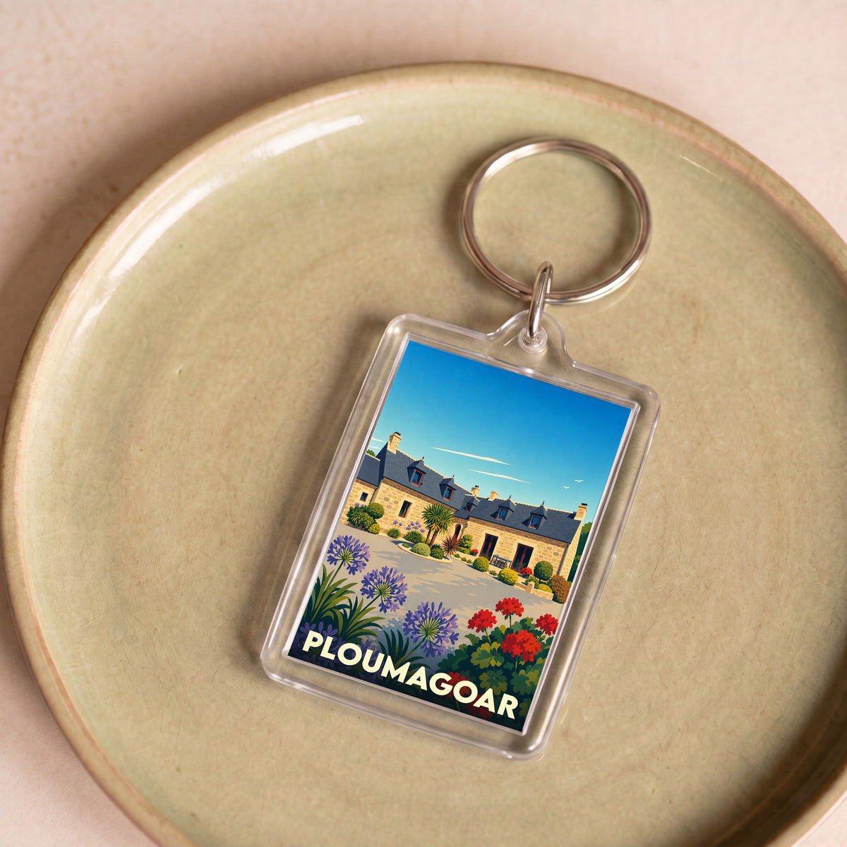 Porte-clés souvenir de la ville de Ploumagoar avec une illustration stylisée d'une maison bretonne fleurie.