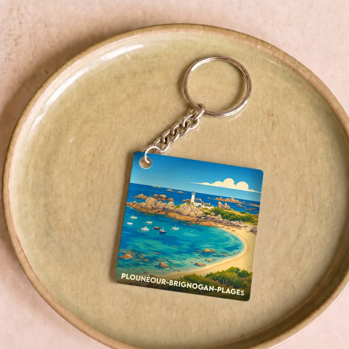 Porte-clés souvenir de la ville de Plounéour-Brignogan-Plages avec une illustration stylisée de sa côte et de son phare.