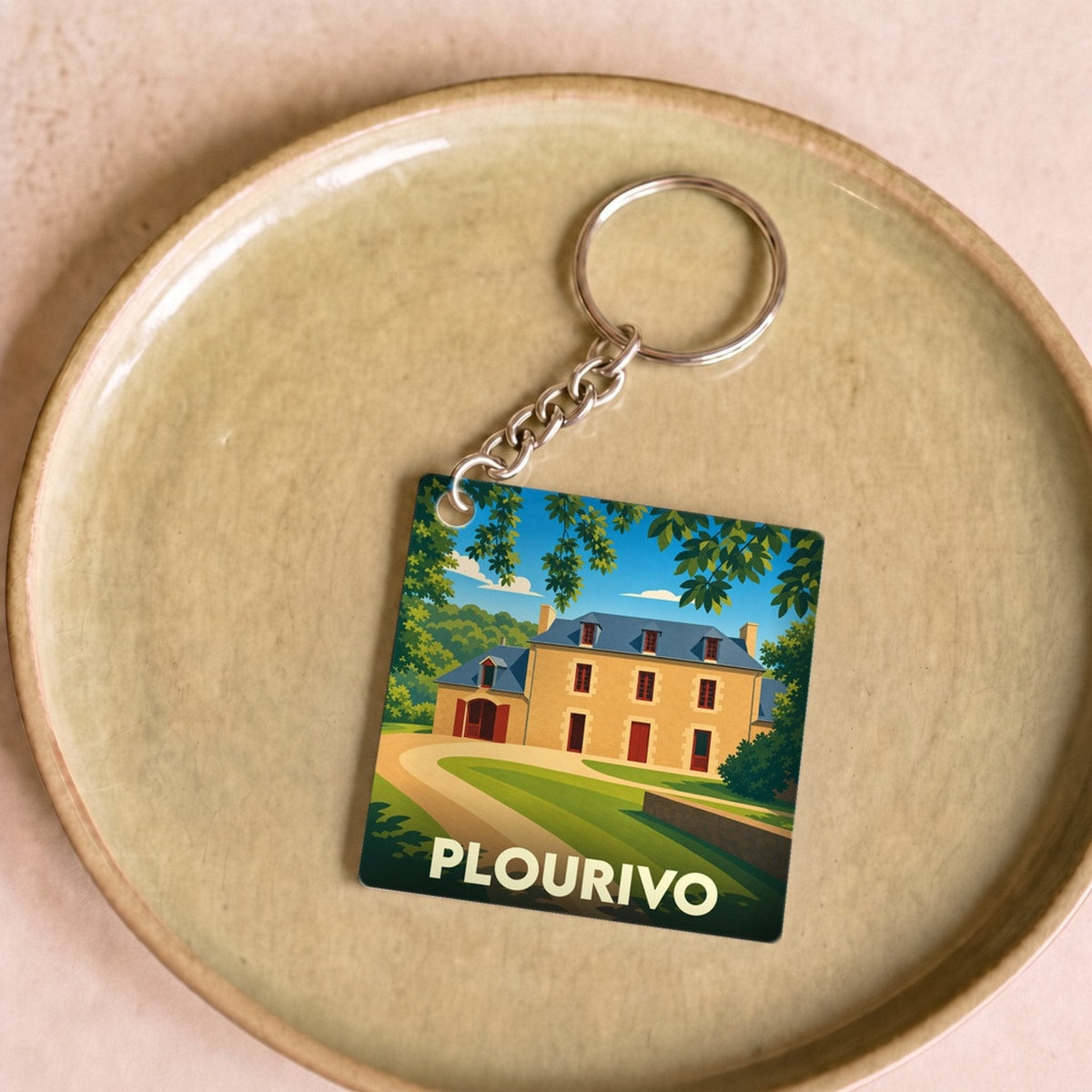 Porte-clés souvenir de la ville de Plourivo avec une illustration stylisée d'un manoir breton.