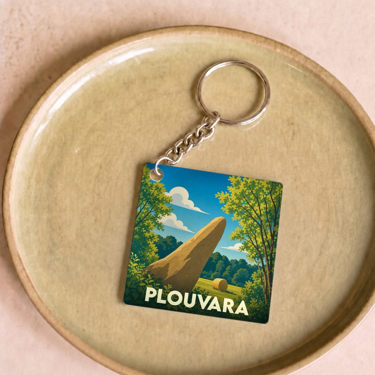 Porte-clés souvenir de la ville de Plouvara avec une illustration stylisée d'un menhir dans la campagne.