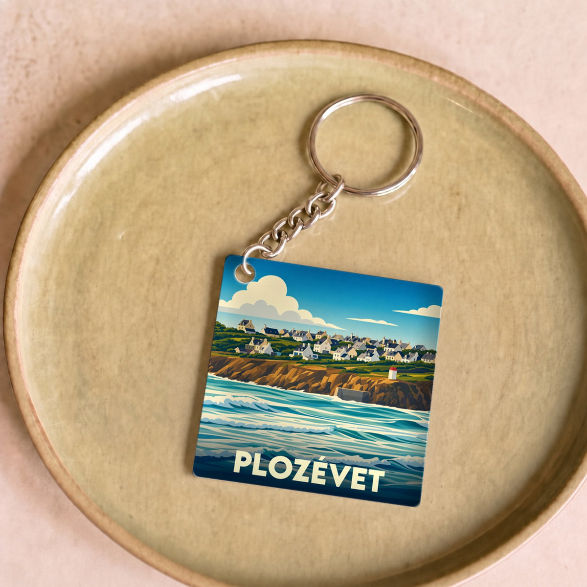 Porte-clés souvenir de la ville de Plozévet avec une illustration stylisée du littoral et de ses maisons.