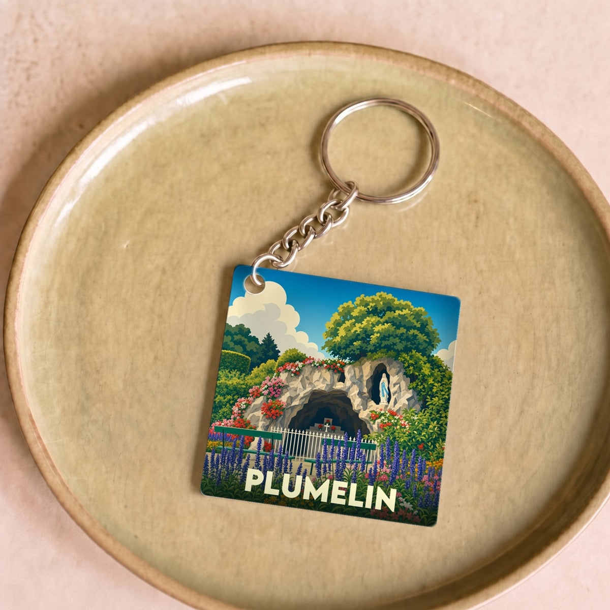 Porte-clés souvenir de la ville de Plumelin avec une illustration stylisée de la grotte locale.