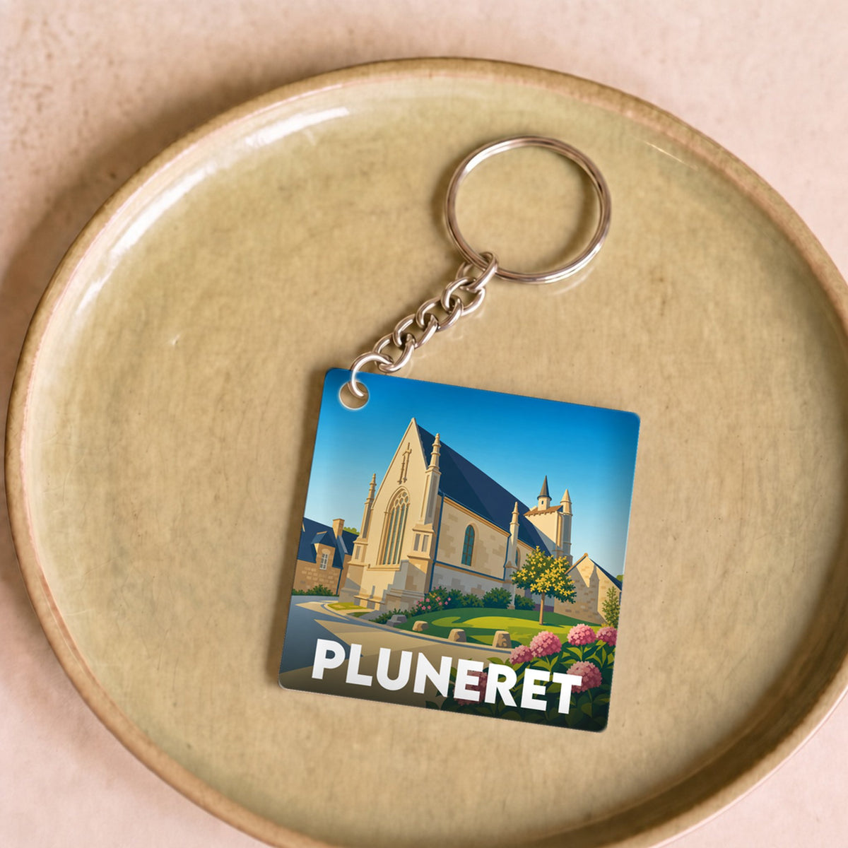 Porte-clés souvenir de la ville de Pluneret avec une illustration stylisée de son église.