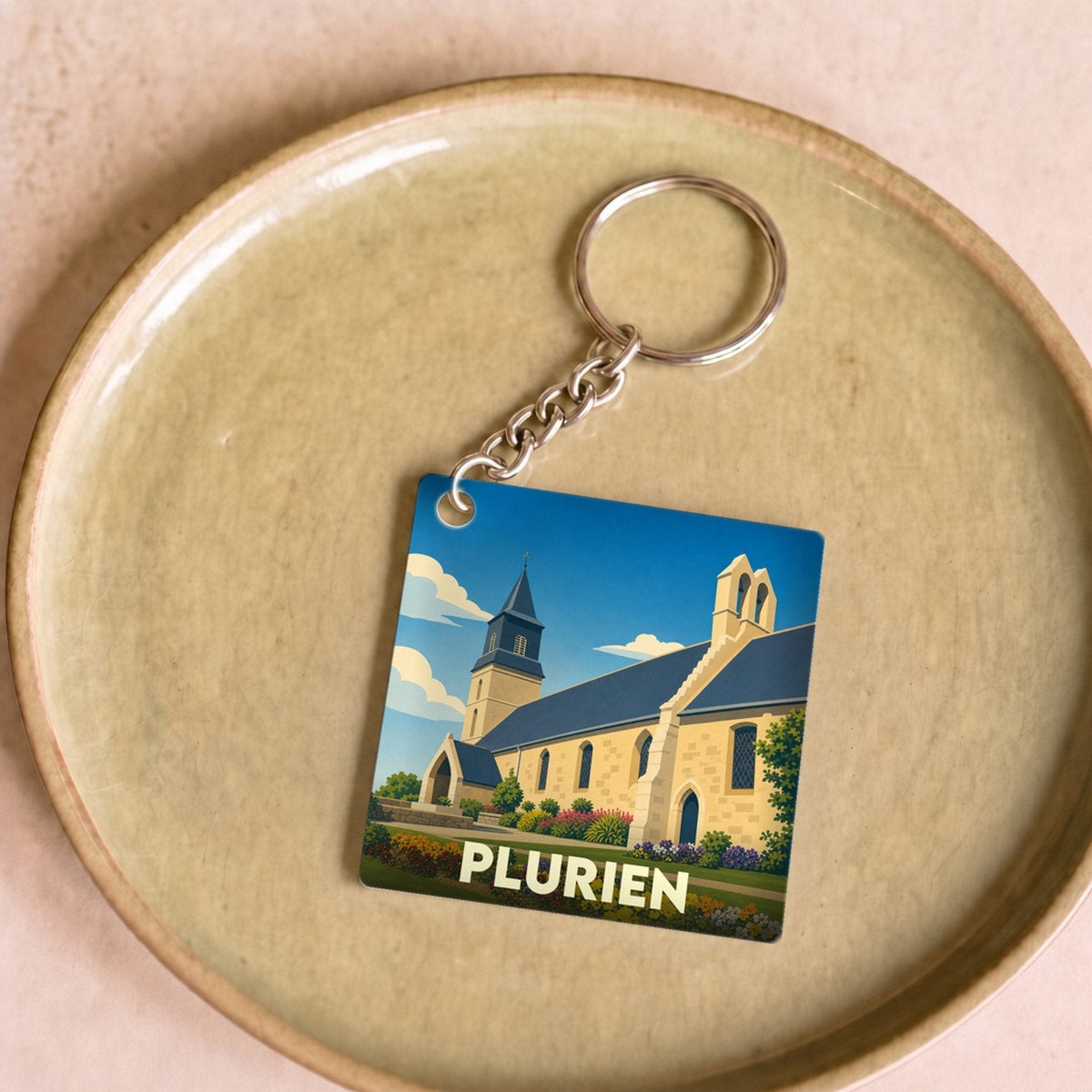 Porte-clés souvenir de la ville de Plurien avec une illustration stylisée de son église.