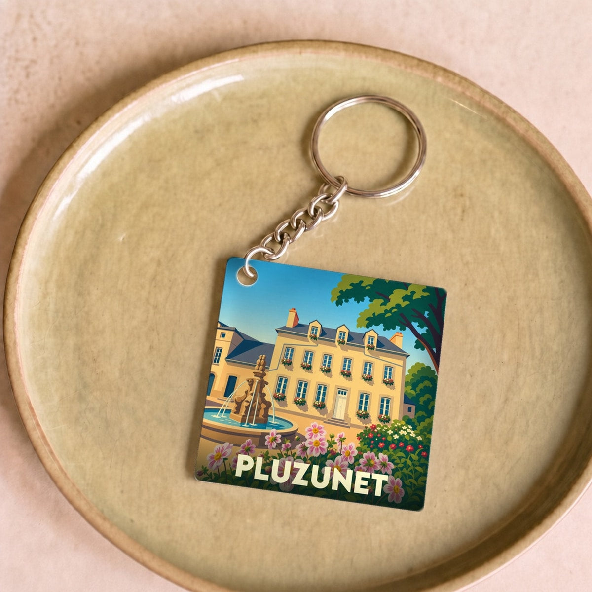 Porte-clés souvenir de la ville de Pluzunet avec une illustration colorée et stylisée.