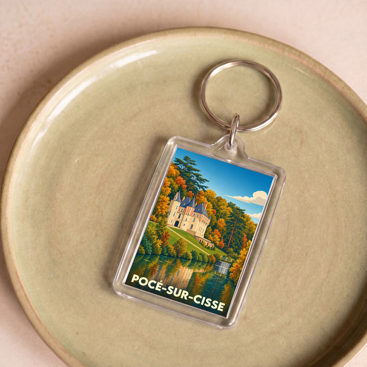 Porte-clés souvenir de Pocé-sur-Cisse avec une illustration stylisée du château et de son reflet dans l'eau.