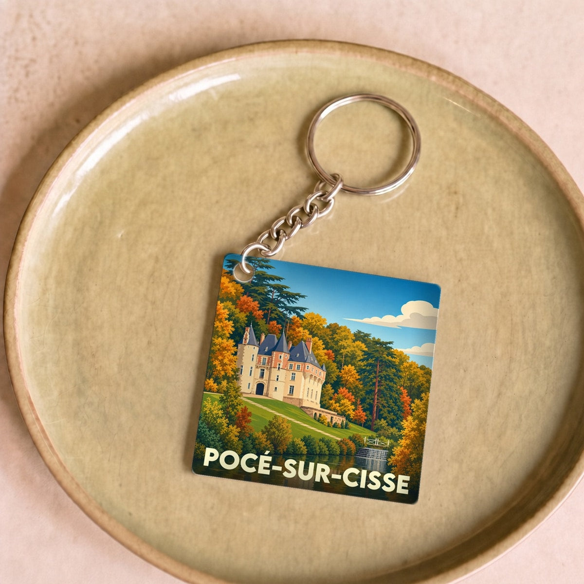 Porte-clés souvenir de Pocé-sur-Cisse avec une illustration stylisée du château et de son reflet dans l'eau.