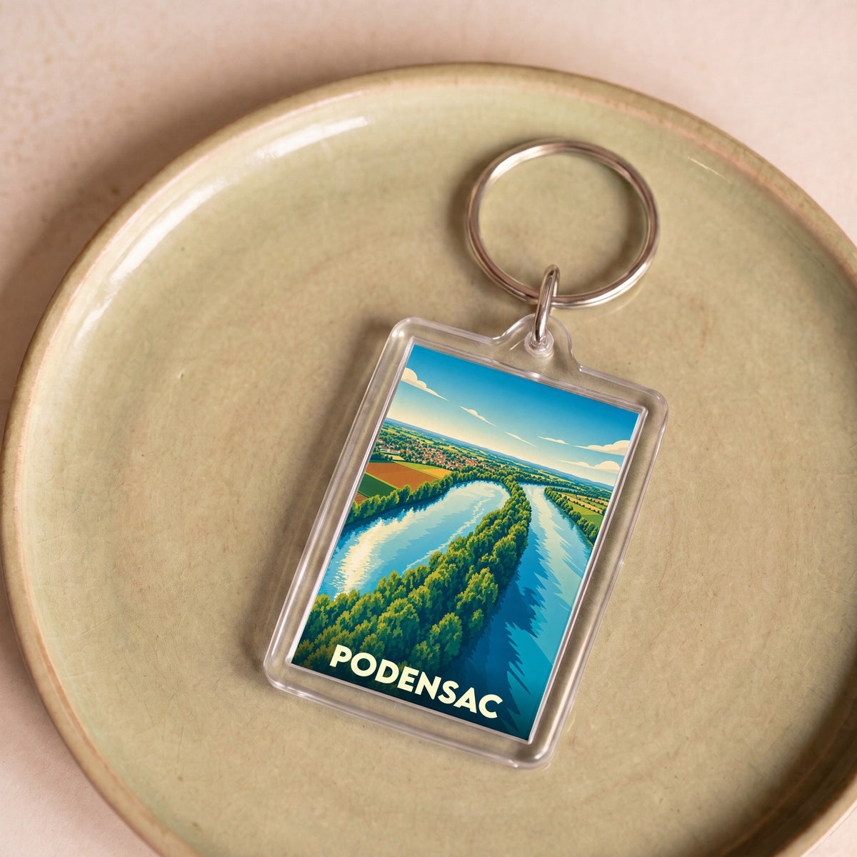 Porte-clés souvenir de la ville de Podensac avec une illustration stylisée d'un paysage fluvial.