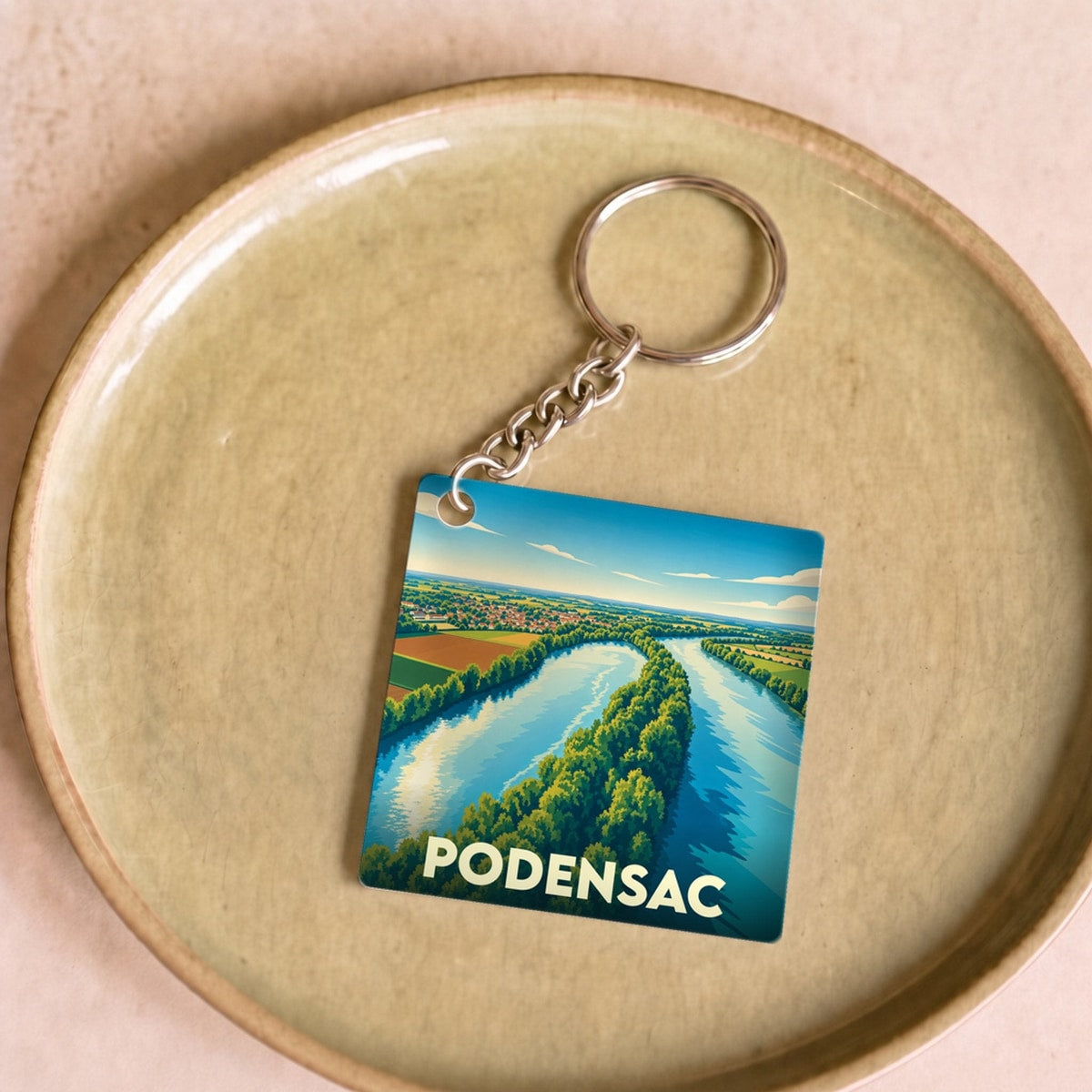 Porte-clés souvenir de la ville de Podensac avec une illustration stylisée d'un paysage fluvial.