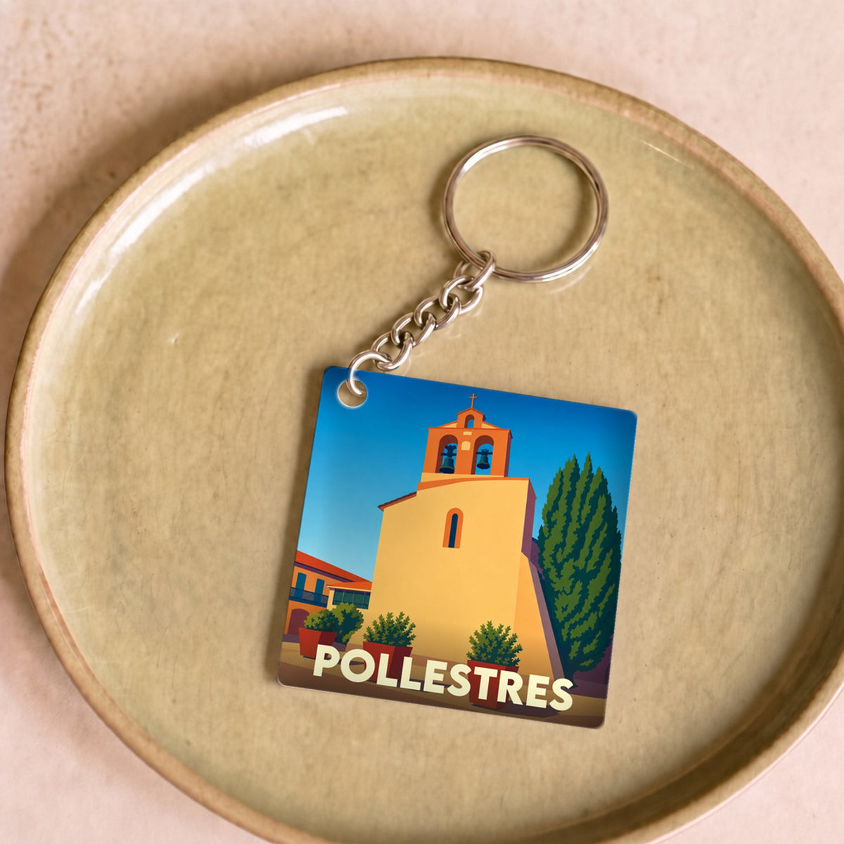 Porte-clés souvenir de la ville de Pollestres avec une illustration stylisée de son église.