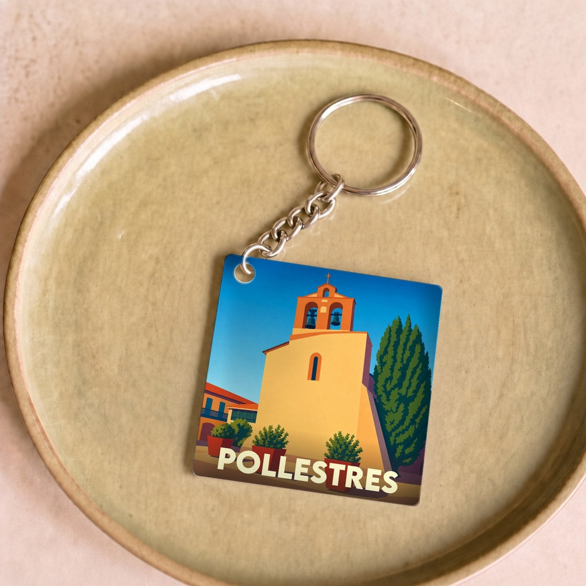 Porte-clés souvenir de la ville de Pollestres avec une illustration stylisée de son église.
