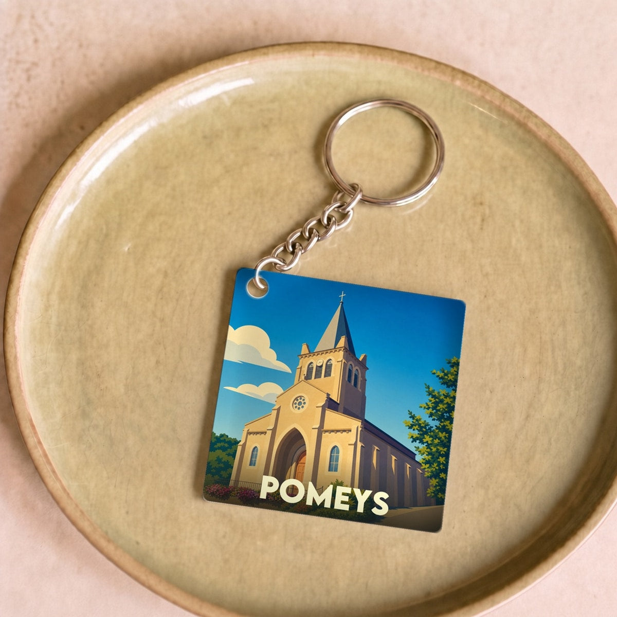 Porte-clés souvenir de la ville de Pomeys avec une illustration stylisée de son église.