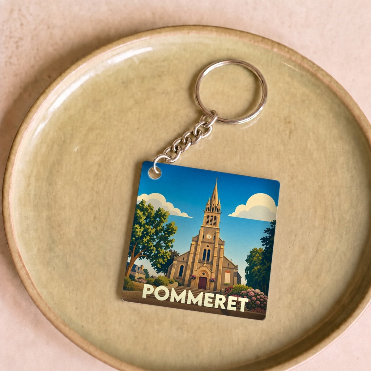 Porte-clés souvenir de la ville de Pommeret avec une illustration stylisée de son église.
