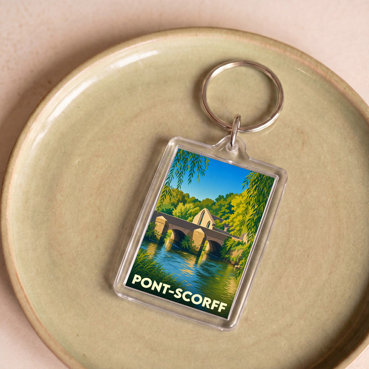 Porte-clés souvenir de la ville de Pont-Scorff avec une illustration stylisée de son pont et de la rivière.