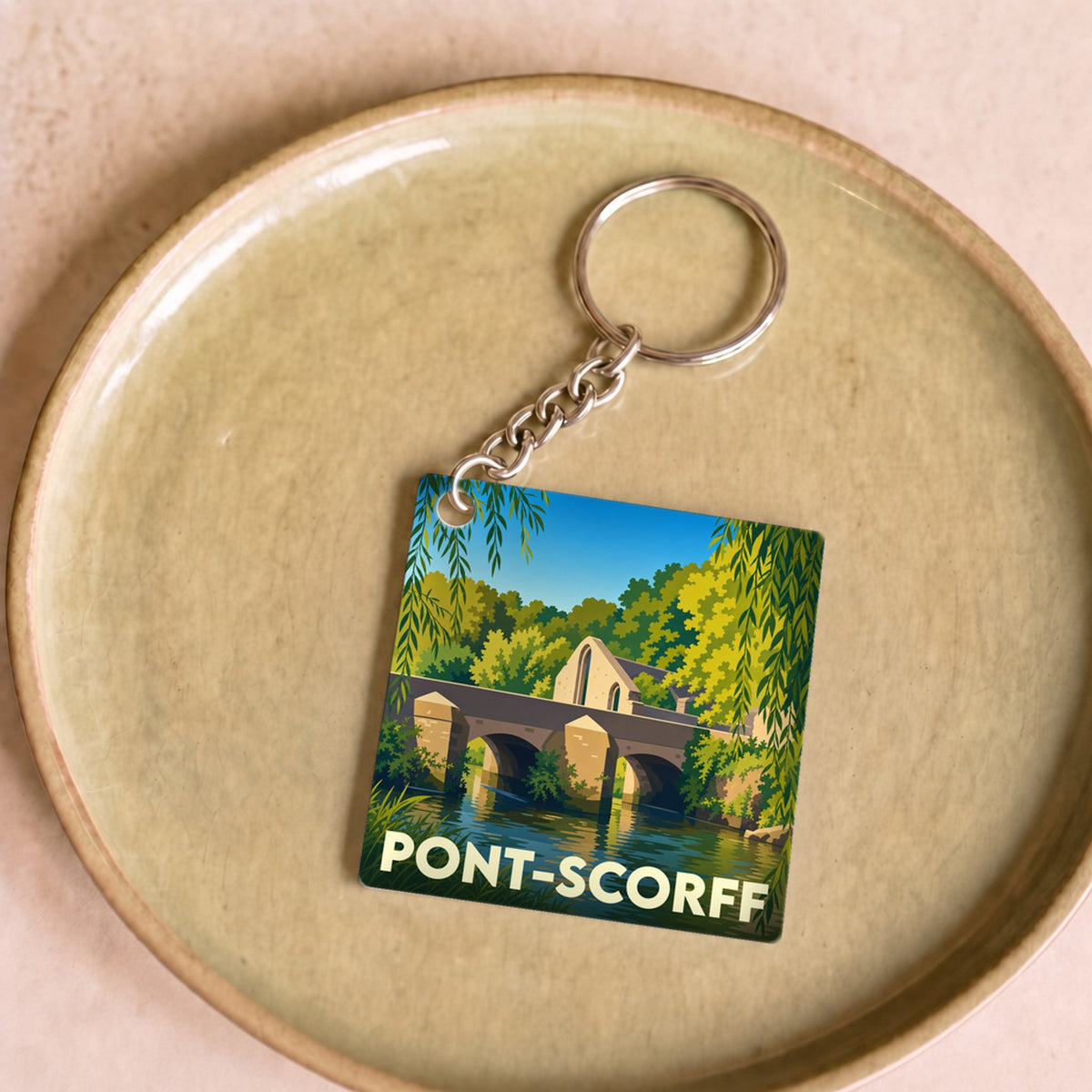 Porte-clés souvenir de la ville de Pont-Scorff avec une illustration stylisée de son pont et de la rivière.