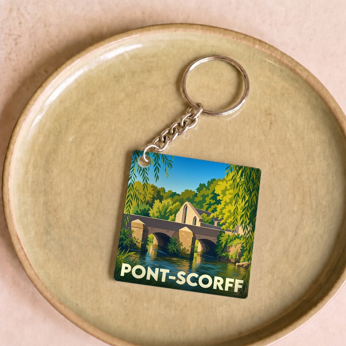 Porte-clés souvenir de la ville de Pont-Scorff avec une illustration stylisée de son pont et de la rivière.