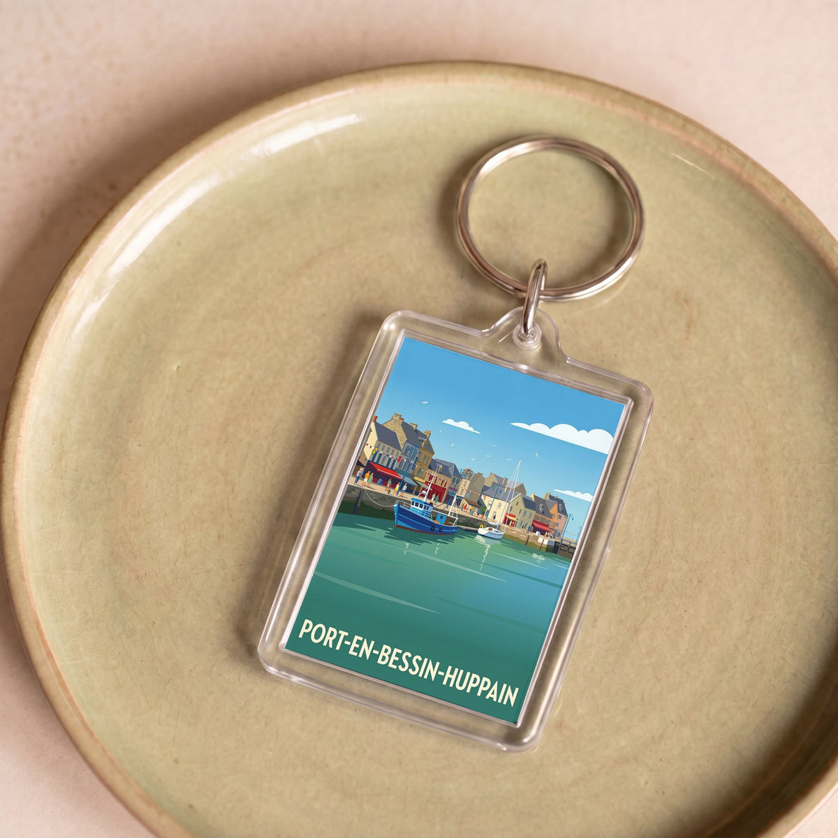 Porte-clés souvenir de la ville de Port-en-Bessin-Huppain avec une illustration stylisée du port.