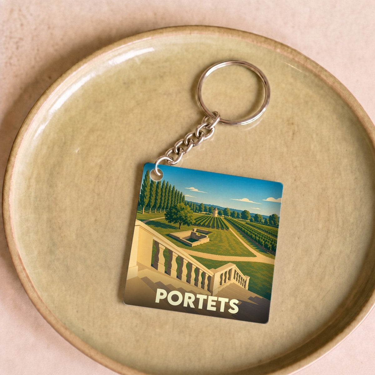 Porte-clés souvenir de la ville de Portets avec une illustration stylisée de son paysage.