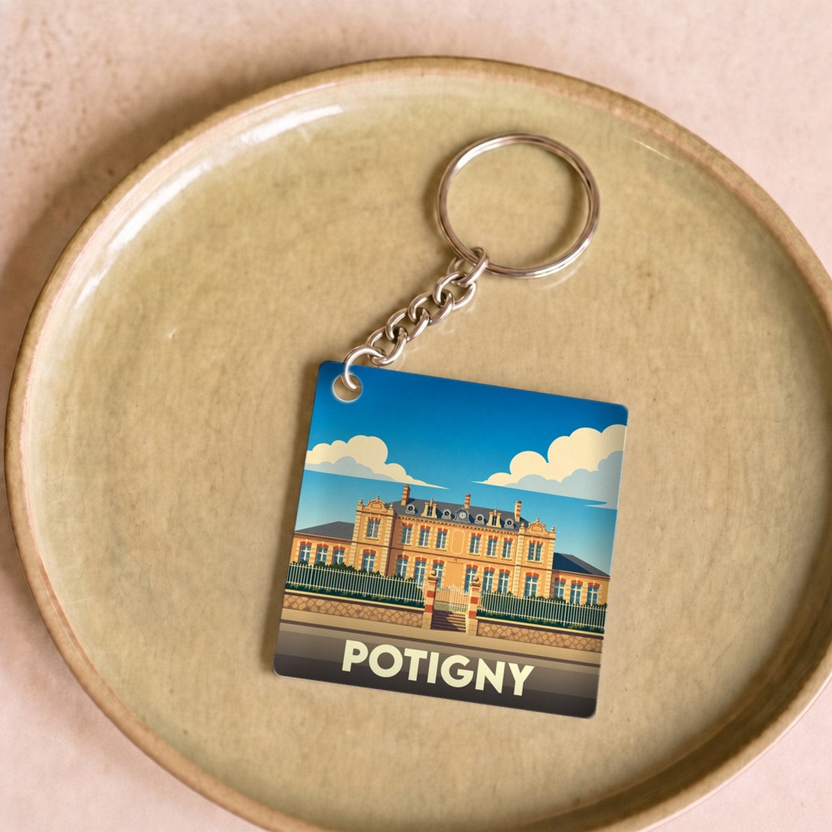 Porte-clés souvenir de la ville de Potigny avec une illustration stylisée d'un bâtiment historique.