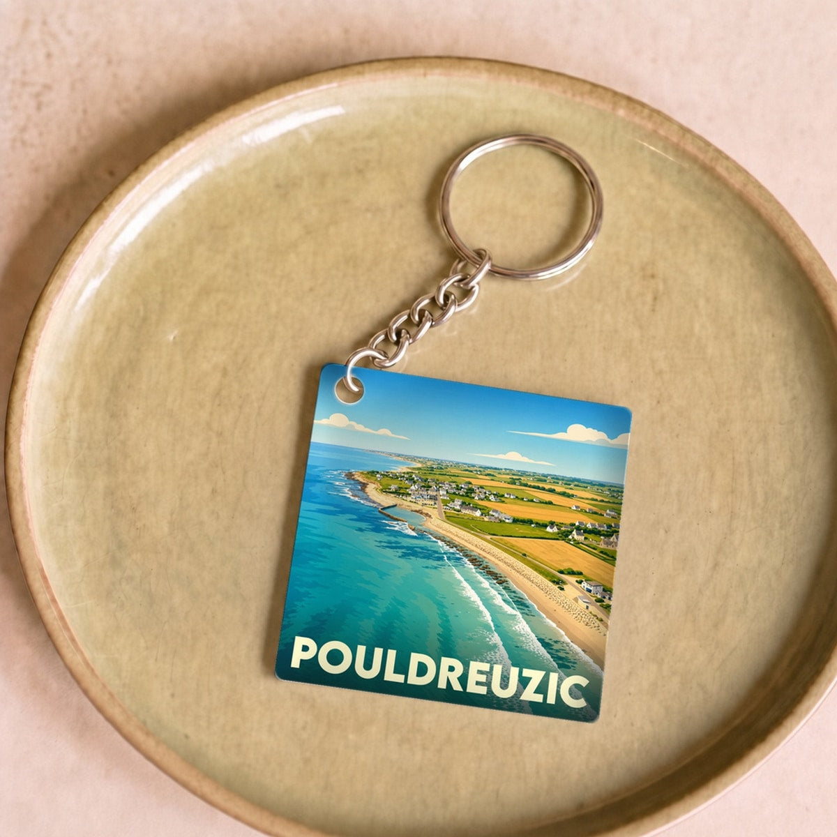 Porte-clés souvenir de la ville de Pouldreuzic avec une illustration stylisée de son littoral.