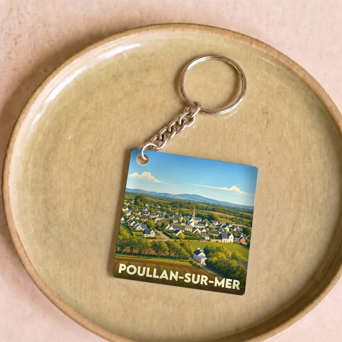 Porte-clés souvenir de la ville de Poullan-sur-Mer avec une illustration stylisée d'un paysage de campagne breton.