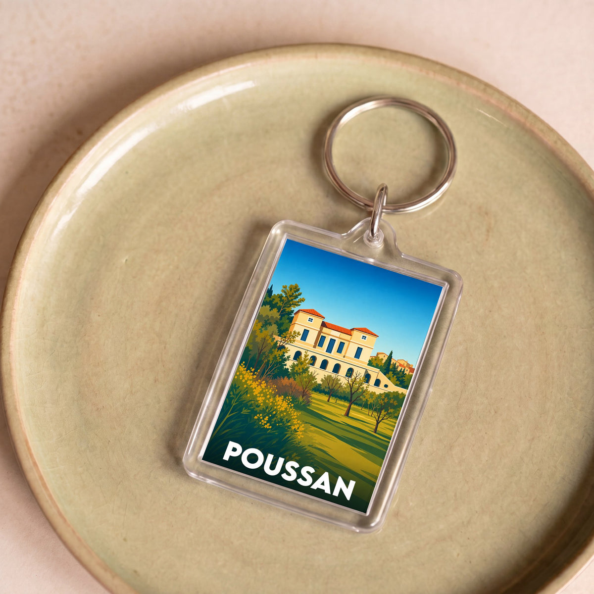 Porte-clés souvenir de la ville de Poussan avec une illustration stylisée.