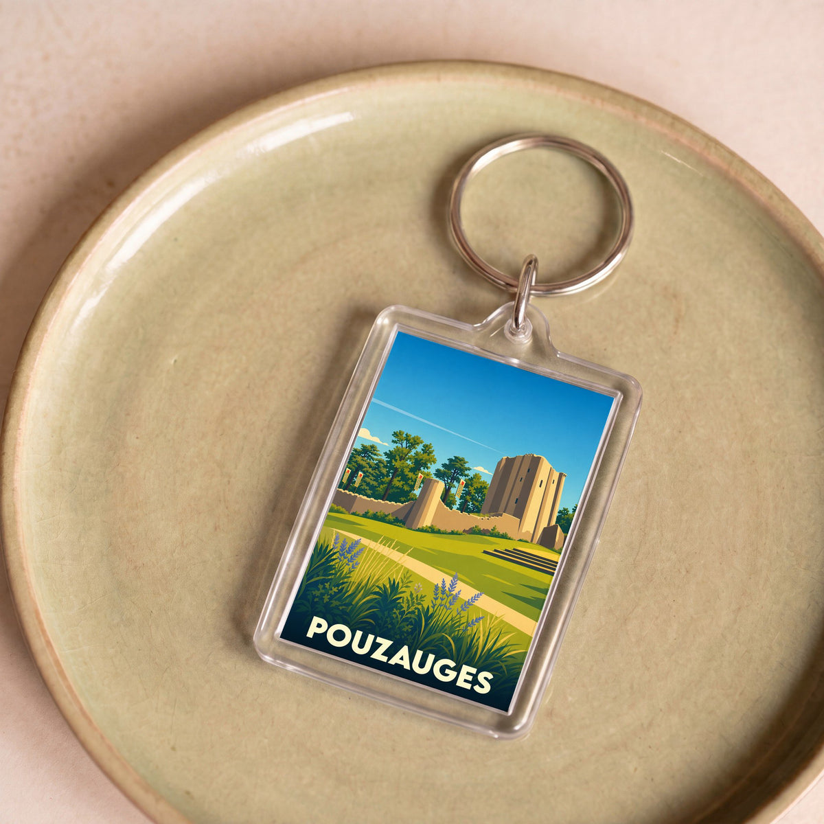 Porte-clés souvenir de la ville de Pouzauges avec une illustration stylisée de son château médiéval.