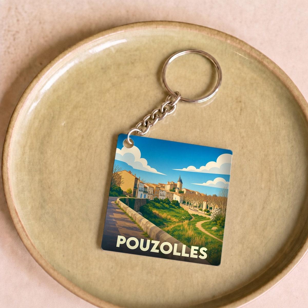 Porte-clés souvenir de la ville de Pouzolles avec une illustration stylisée.