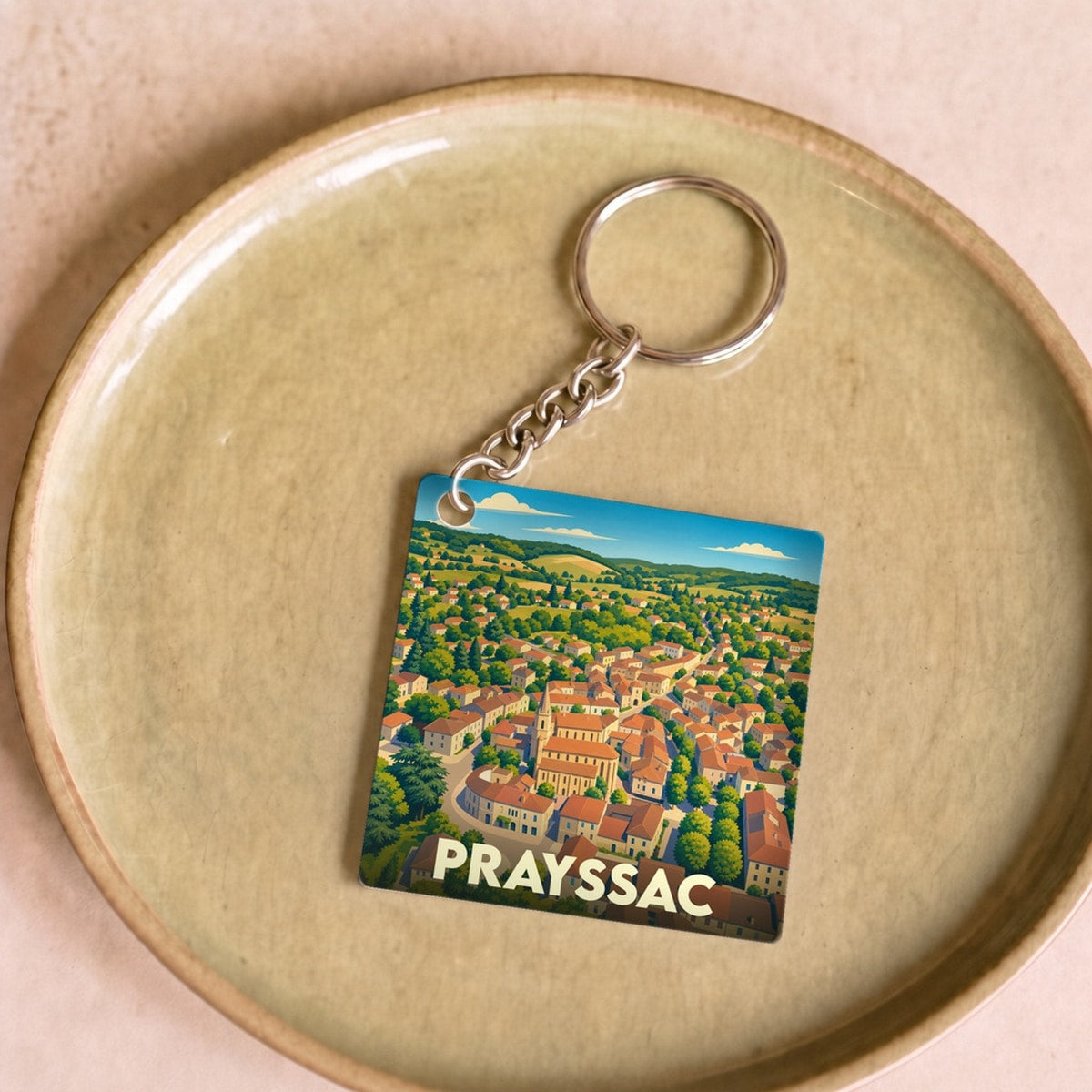 Porte-clés souvenir de la ville de Prayssac avec une illustration stylisée.