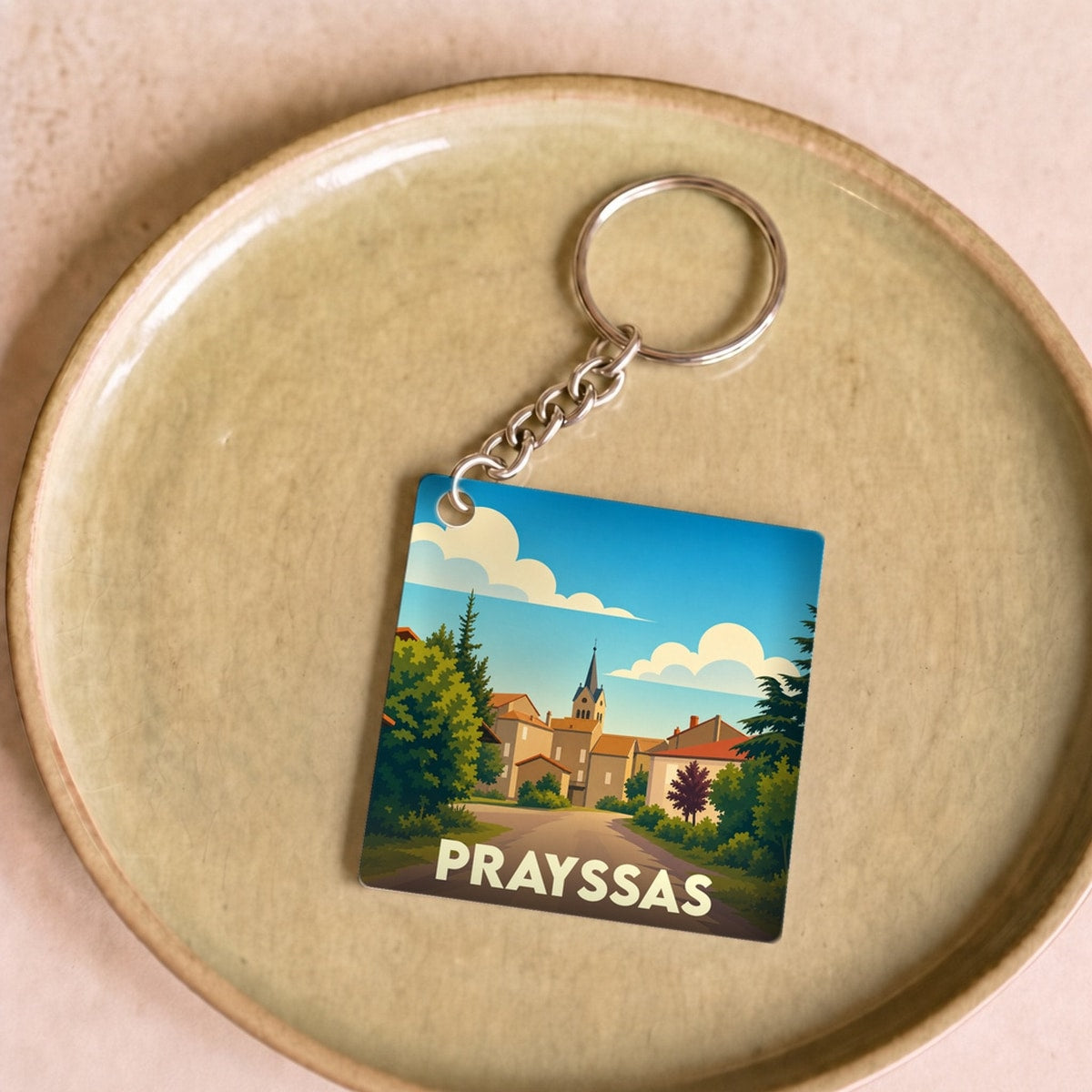 Porte-clés souvenir de la ville de Prayssas avec une illustration stylisée.
