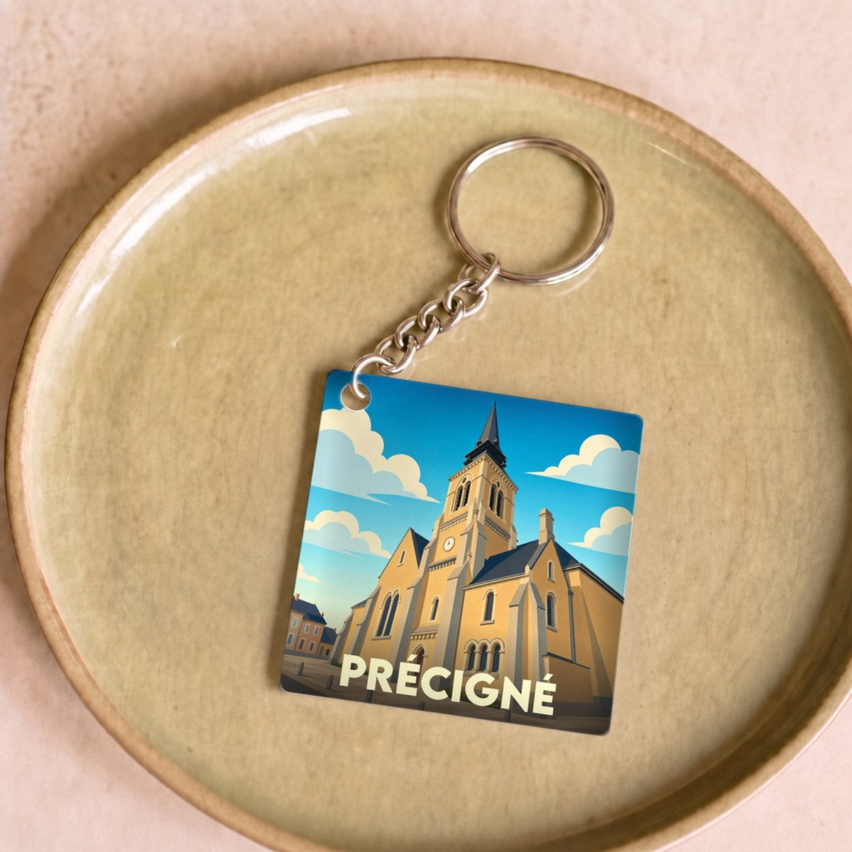 Porte-clés souvenir de la ville de Précigné avec une illustration stylisée de son église.