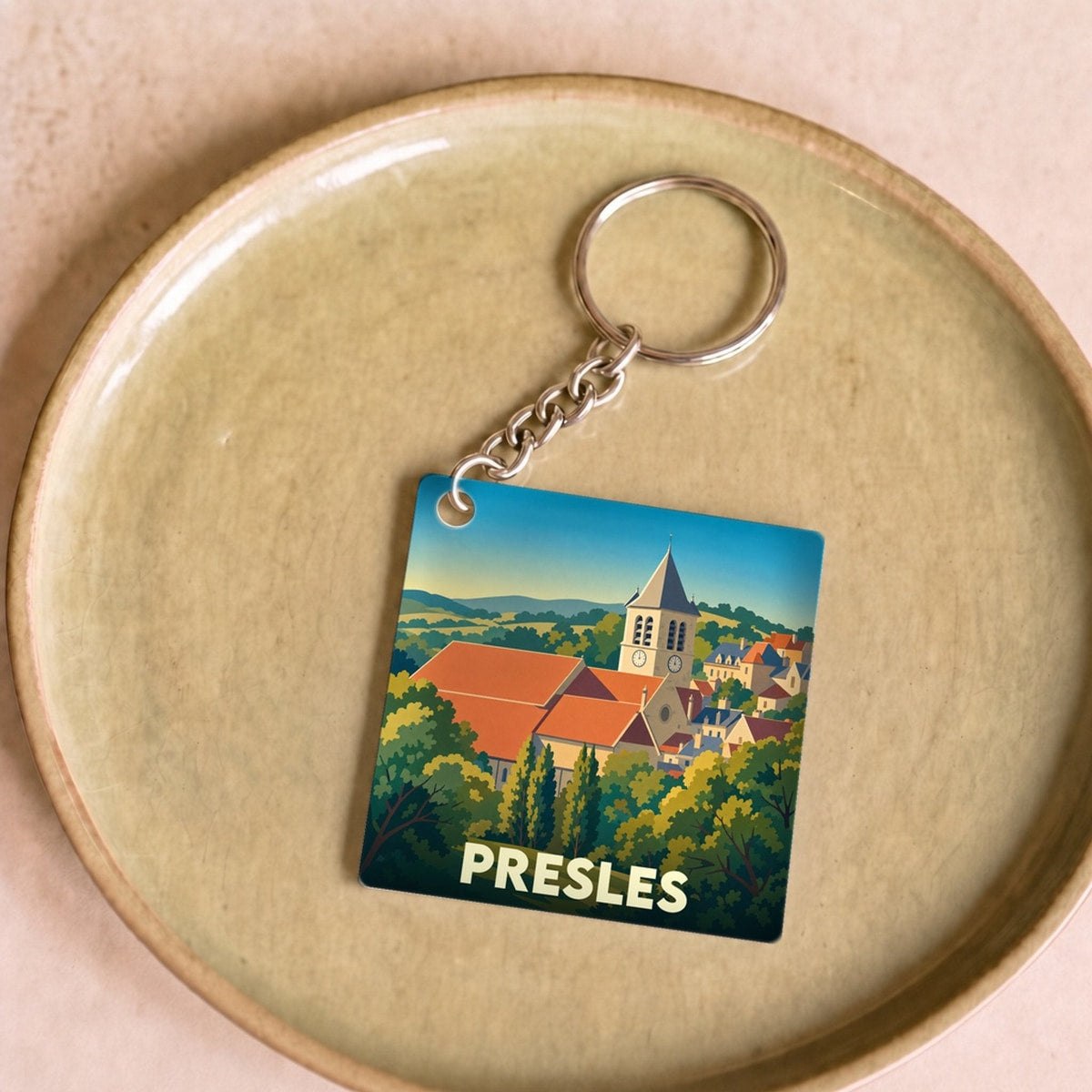 Porte-clés souvenir de la ville de Presles avec une illustration stylisée de son église et de son paysage vallonné.