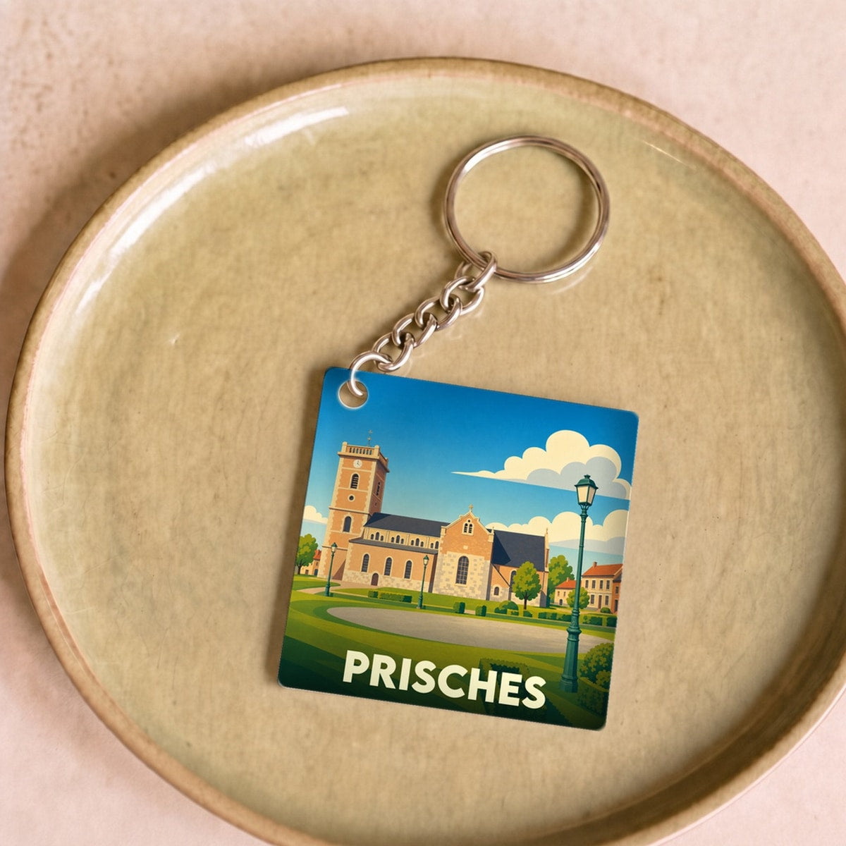 Porte-clés souvenir de la ville de Prisches avec une illustration stylisée de son église.