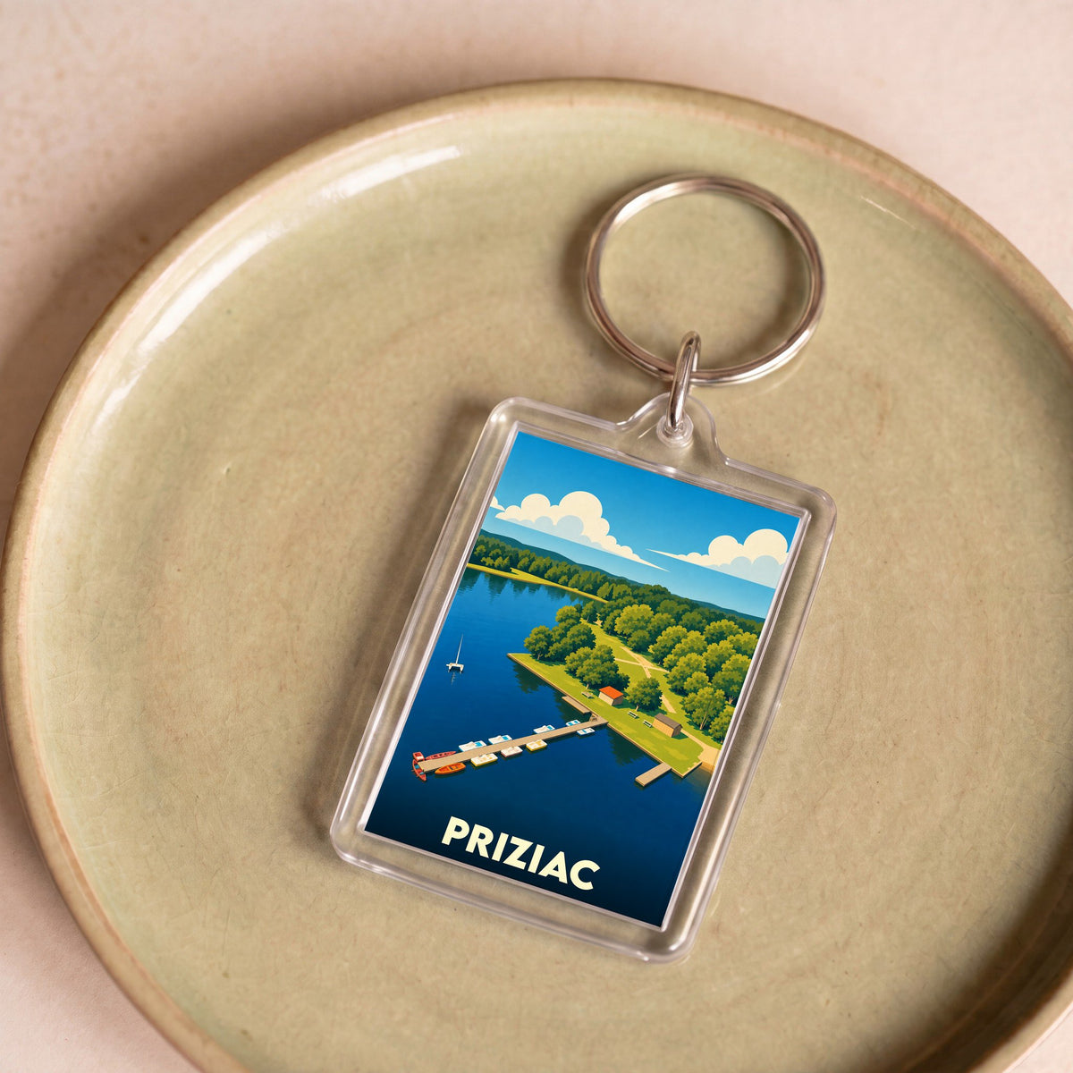 Porte-clés souvenir de la ville de Priziac avec une illustration stylisée d'un lac et de son ponton.