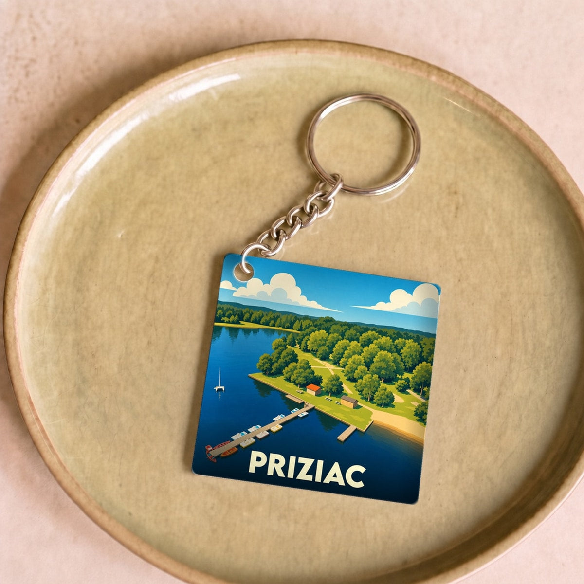 Porte-clés souvenir de la ville de Priziac avec une illustration stylisée d'un lac et de son ponton.
