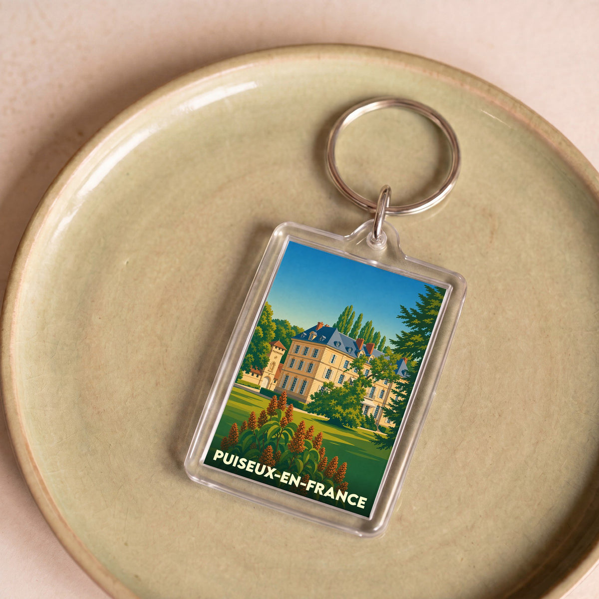 Porte-clés souvenir de la ville de Puiseux-en-France avec une illustration stylisée.