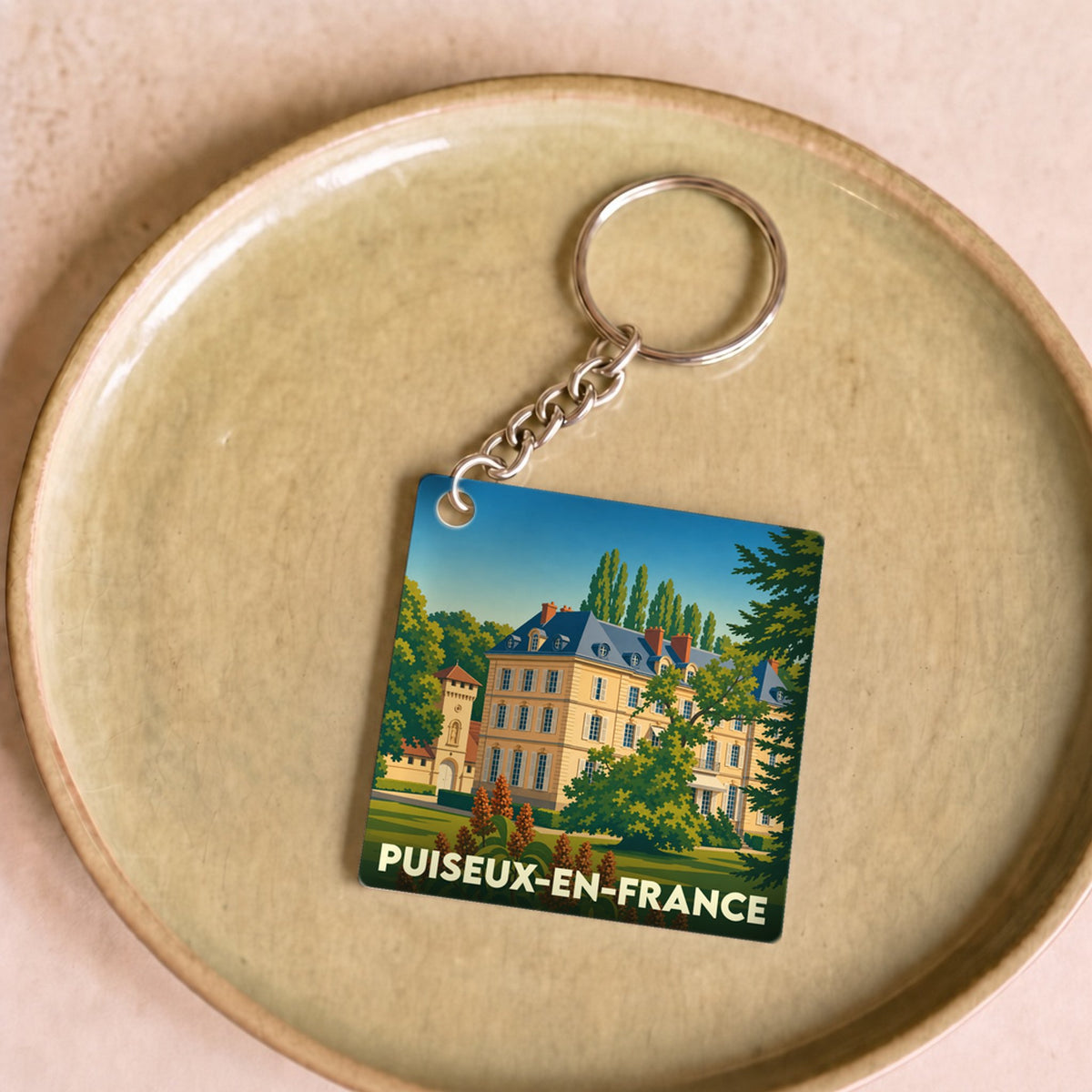 Porte-clés souvenir de la ville de Puiseux-en-France avec une illustration stylisée.