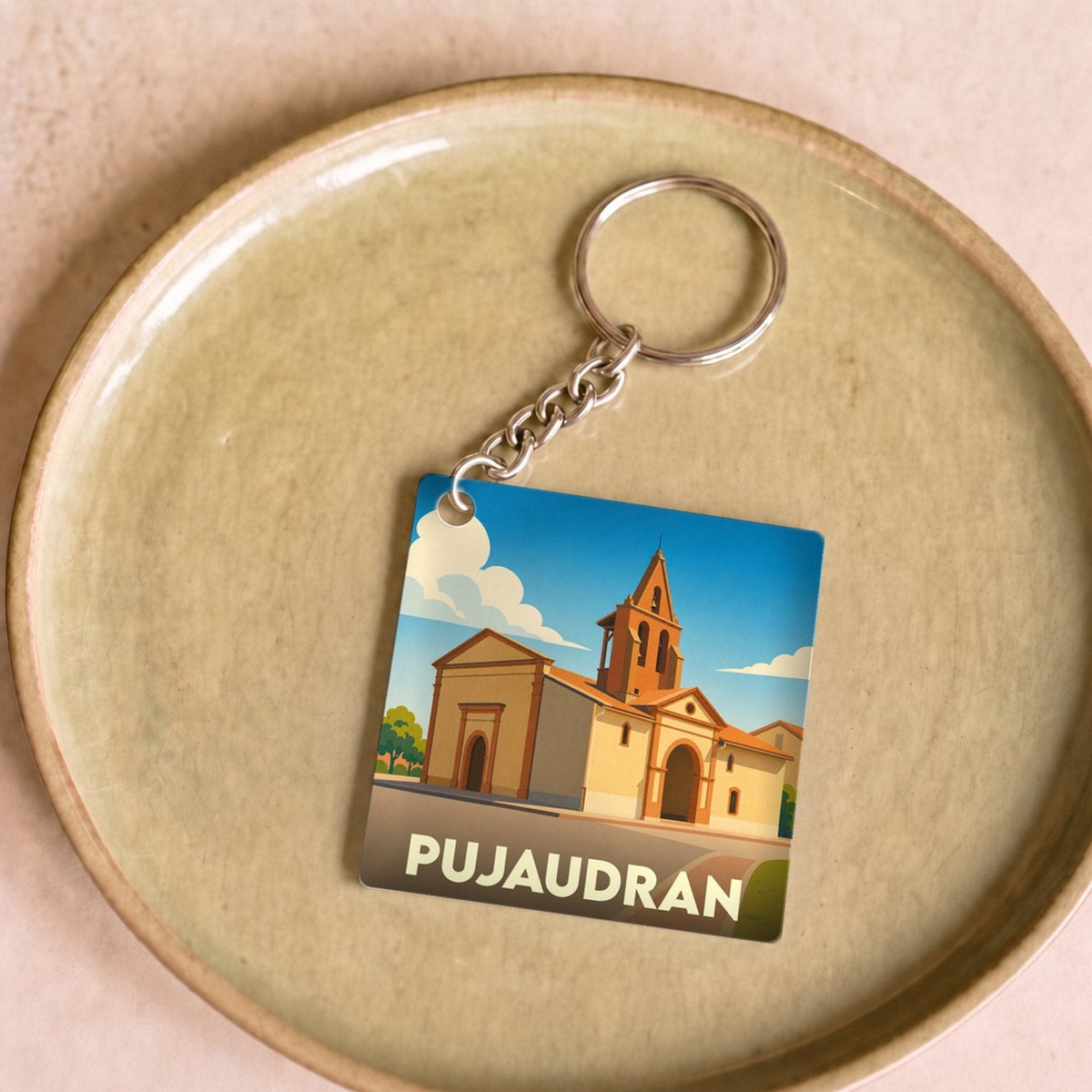 Porte-clés souvenir de la ville de Pujaudran avec une illustration stylisée de son église.