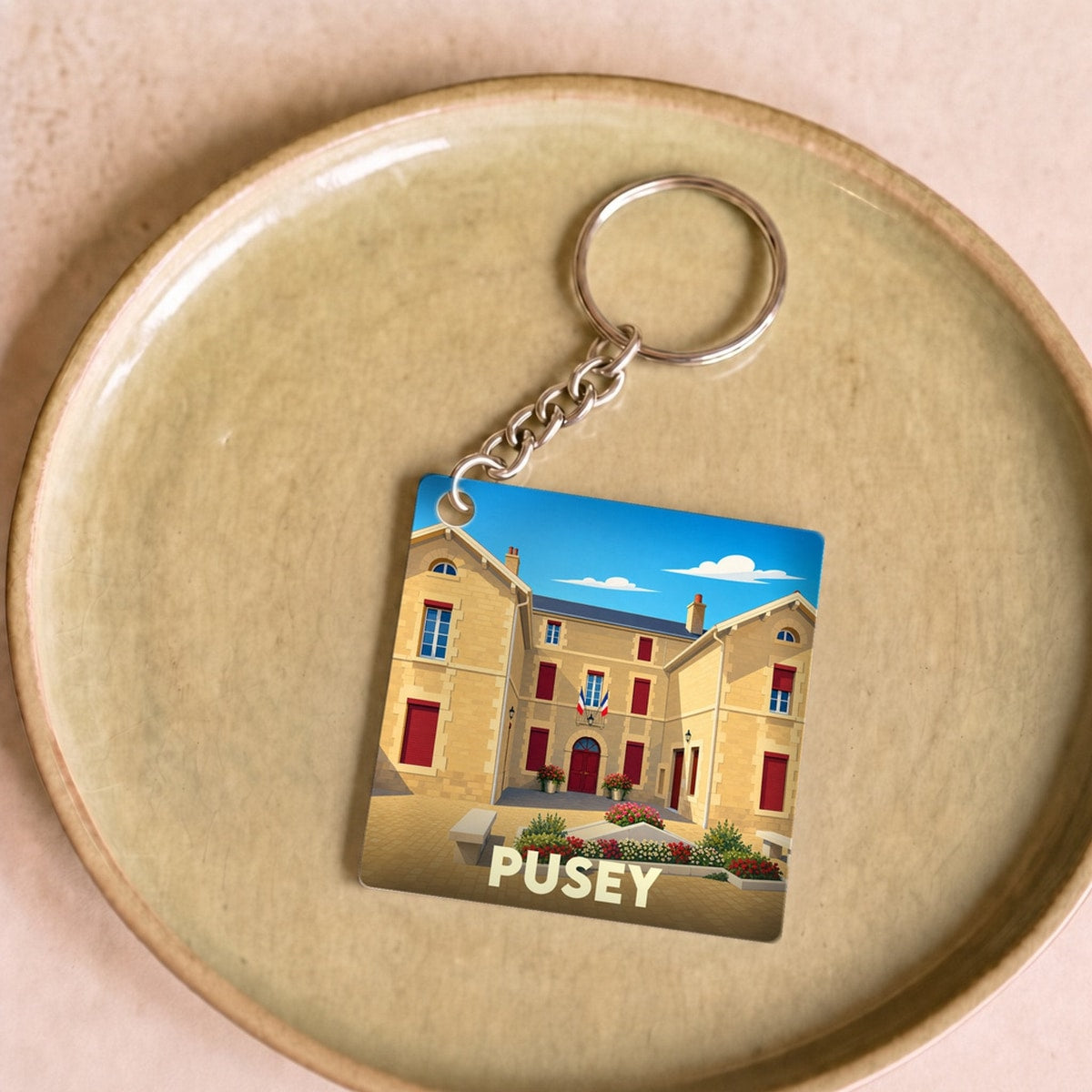 Porte-clés souvenir de la ville de Pusey avec une illustration stylisée de son hôtel de ville.