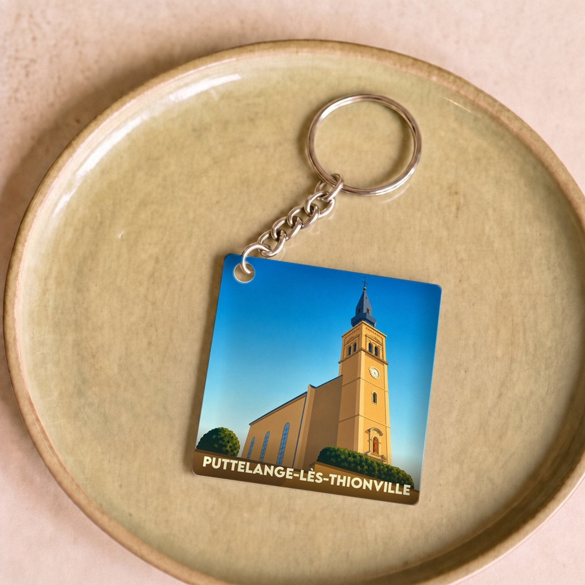 Porte-clés souvenir de la ville de Puttelange-lès-Thionville avec une illustration stylisée de son église.
