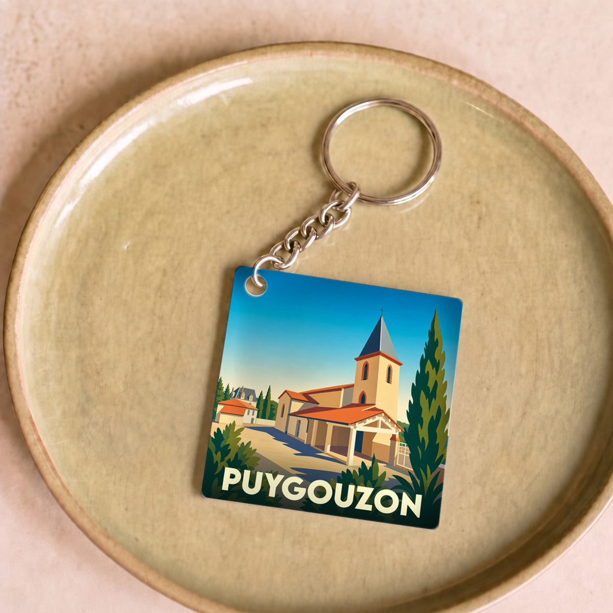 Porte-clés souvenir de la ville de Puygouzon avec une illustration stylisée.