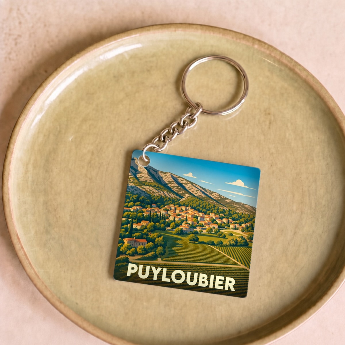 Porte-clés souvenir de la ville de Puyloubier avec une illustration stylisée de ses paysages provençaux.