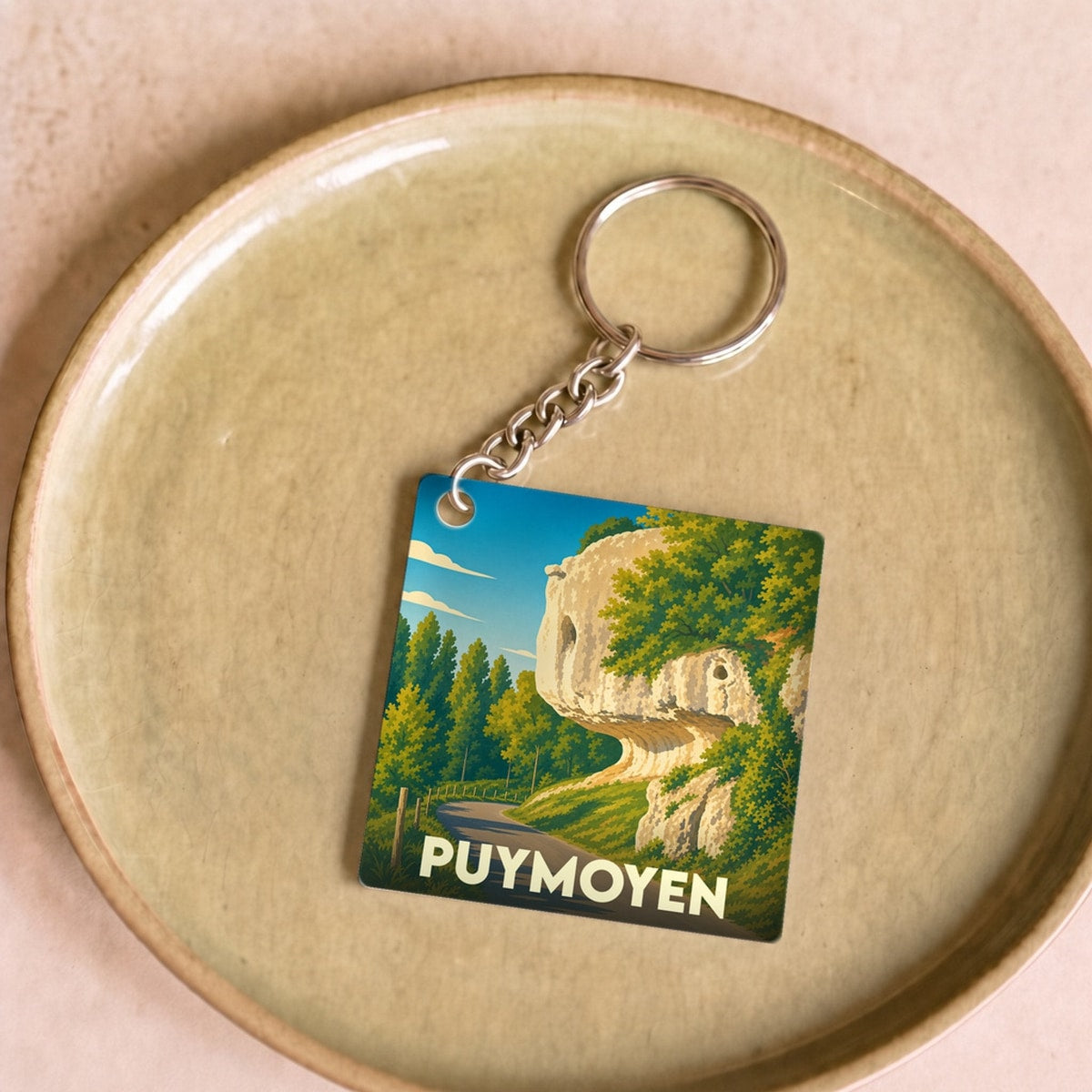 Porte-clés souvenir de la ville de Puymoyen avec une illustration stylisée d'un paysage rocheux.