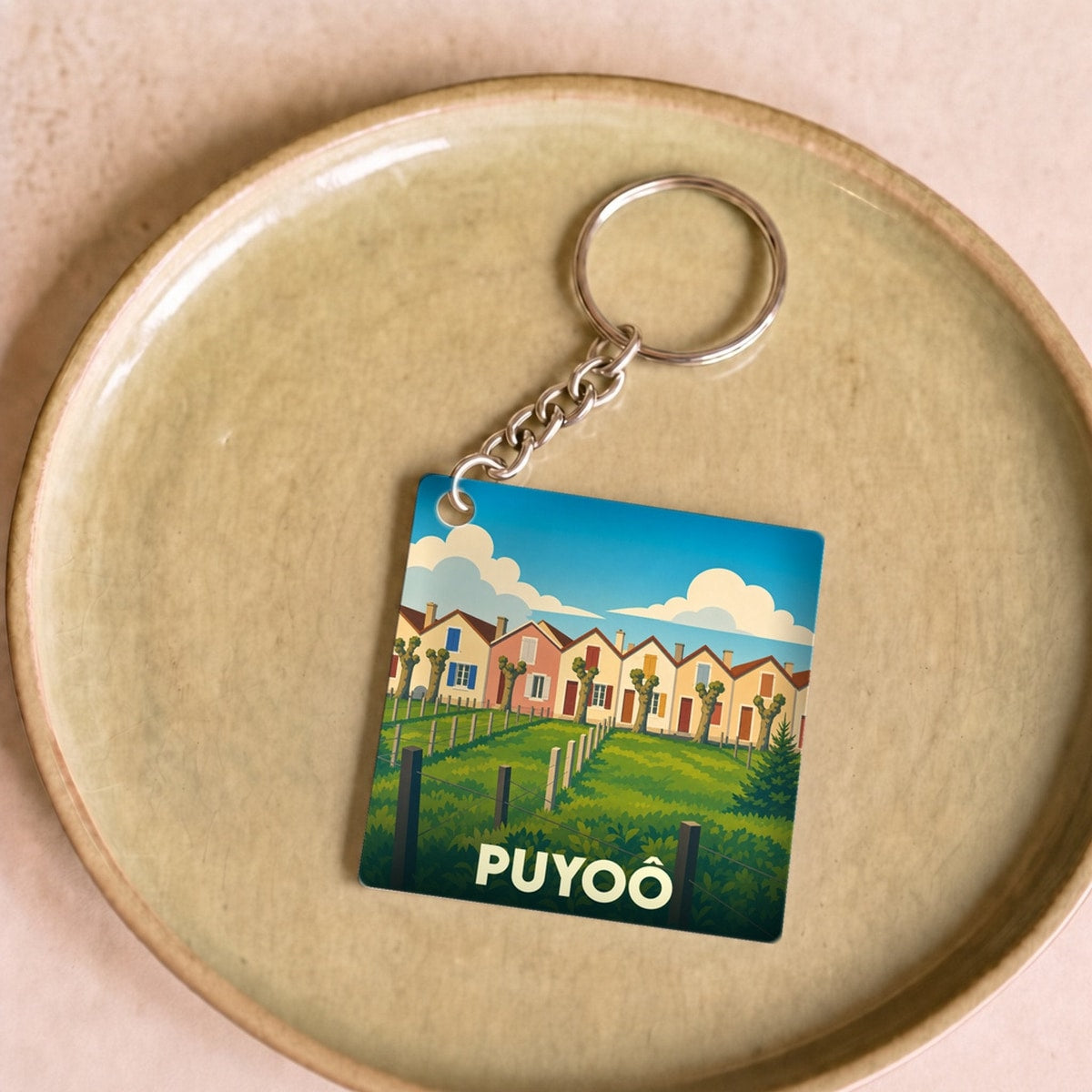 Porte-clés souvenir de la ville de Puyoô avec une illustration stylisée de maisons colorées.