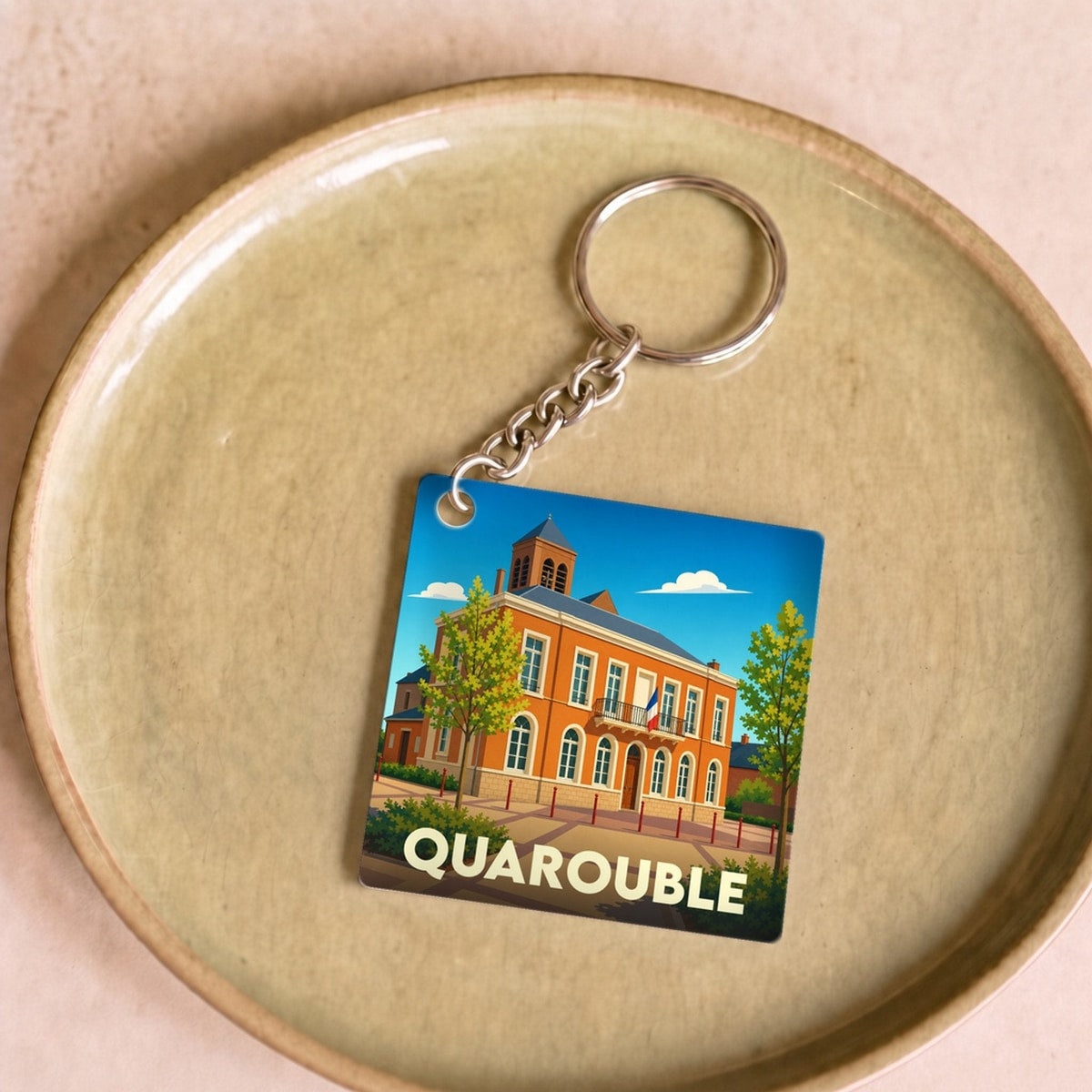 Porte-clés souvenir de la ville de Quarouble avec une illustration stylisée de son hôtel de ville.