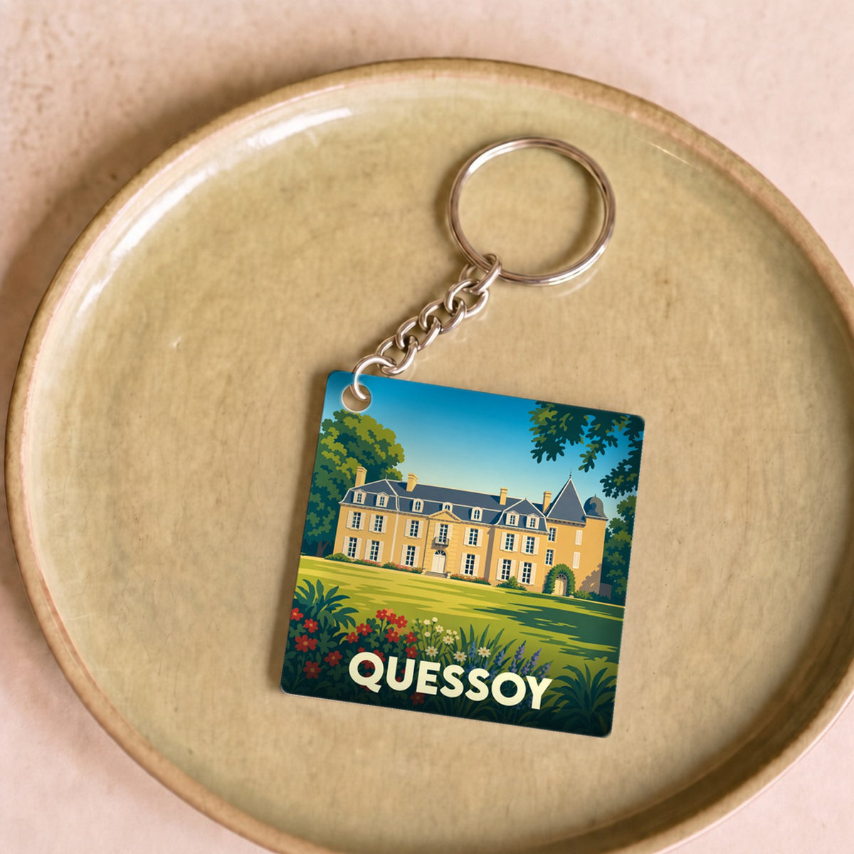 Porte-clés souvenir de la ville de Quessoy avec une illustration stylisée d'un château.
