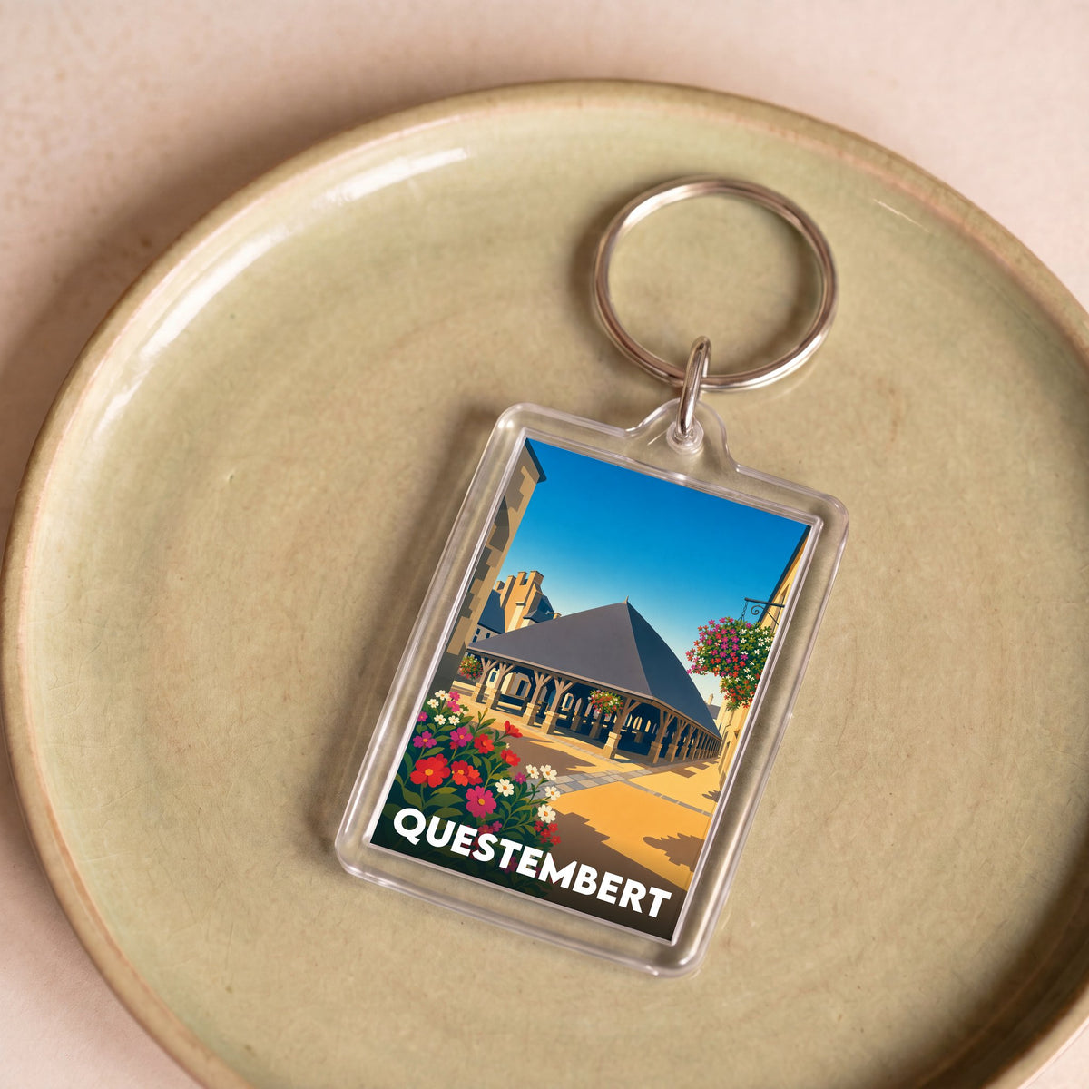 Porte-clés souvenir de la ville de Questembert avec une illustration stylisée de ses halles historiques.