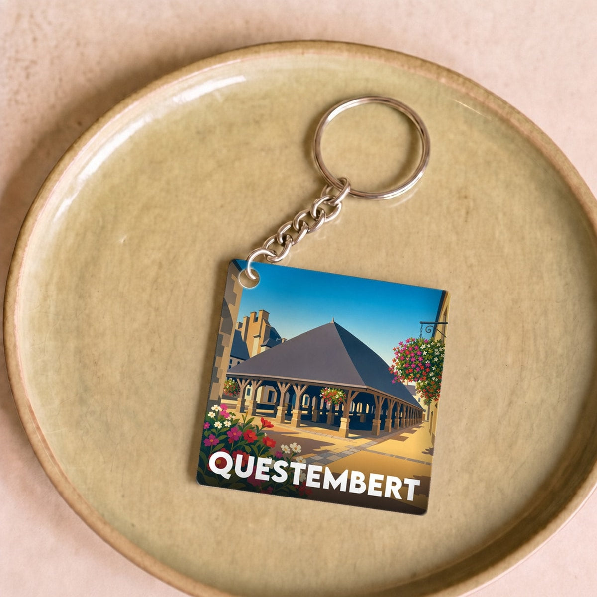 Porte-clés souvenir de la ville de Questembert avec une illustration stylisée de ses halles historiques.