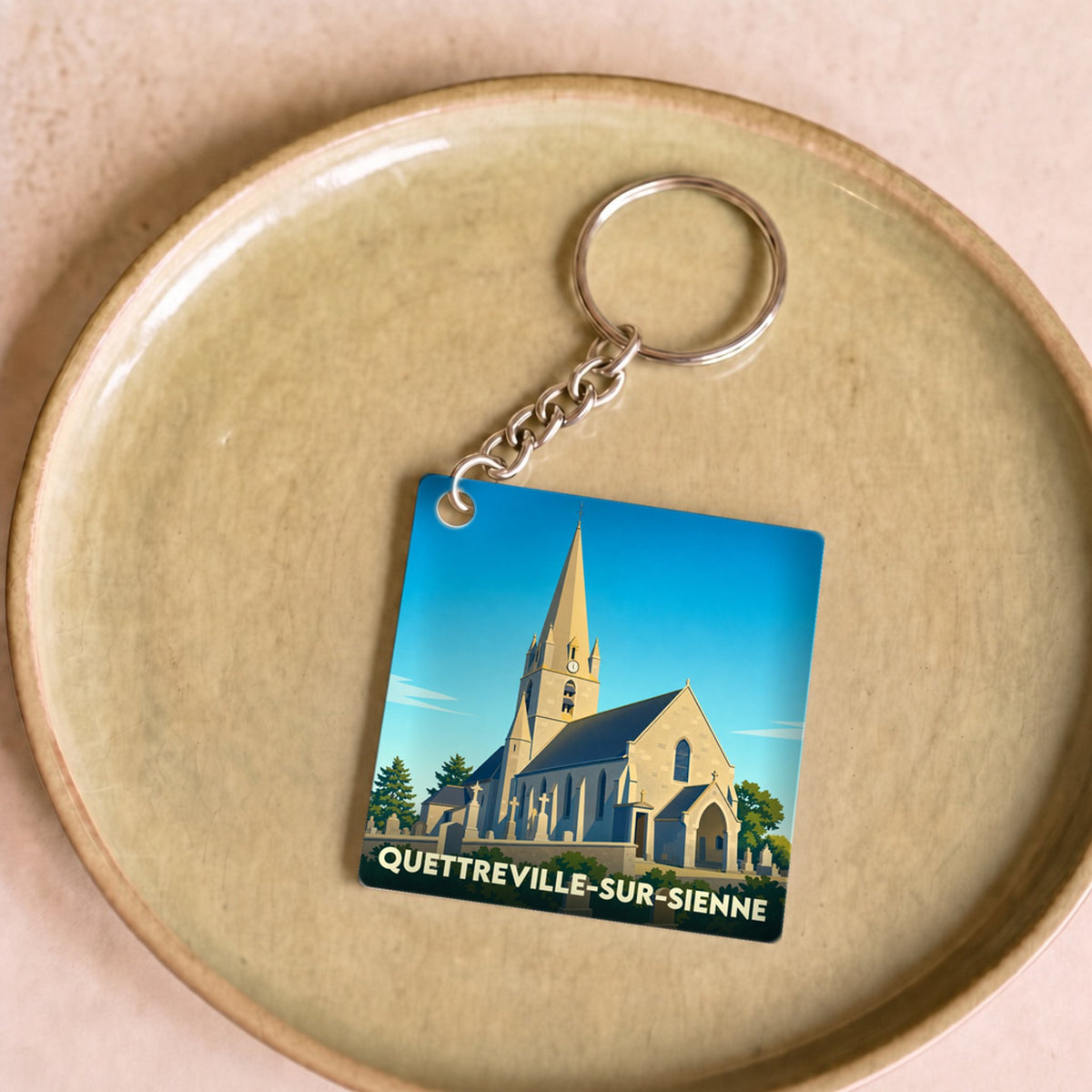 Porte-clés souvenir de la ville de Quettreville-sur-Sienne avec une illustration stylisée de son église.