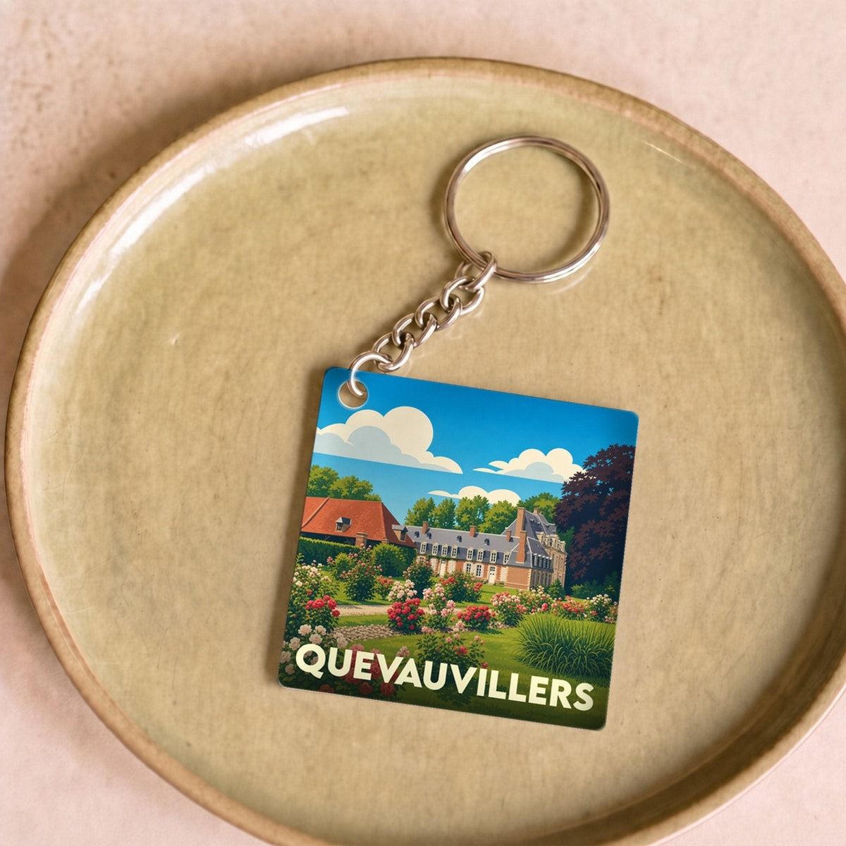 Porte-clés souvenir de la ville de Quevauvillers avec une illustration stylisée de son château et de ses jardins.